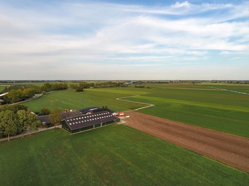 An aerial shot of a green farm under a cloudy sky