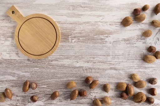 A high angle shot of a wooden plate and some hazelnuts and almonds on a wooden surface