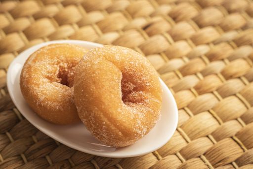 A high angle closeup shot of delicious homemade donuts covered with sugar on a woven surface
