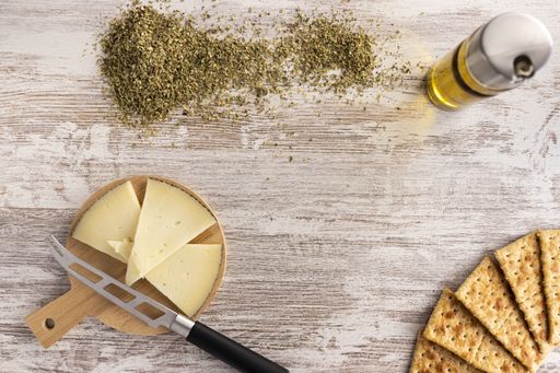 A high angle shot of biscuits, cheese, olive oil, and seeds on a wooden surface