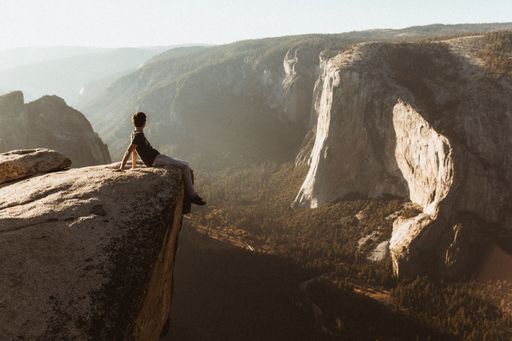 A young male hiker sitting on the edge of a cliff in Yosemite National Park