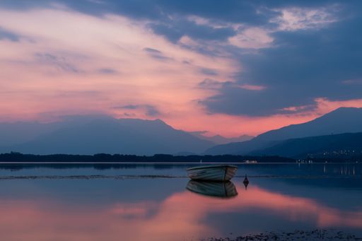 An unmanned boat floating on a calm coast under a beautiful sunset