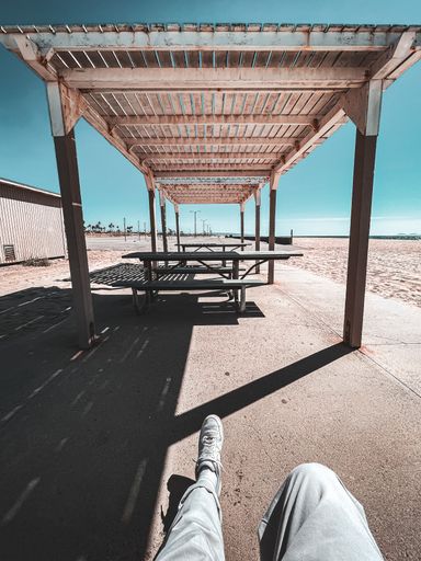 A vertical shot of the legs against empty chairs under a wooden cover. Ventura Beach, San Diego.