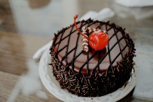 A closeup shot of a small chocolate pastry with a cherry