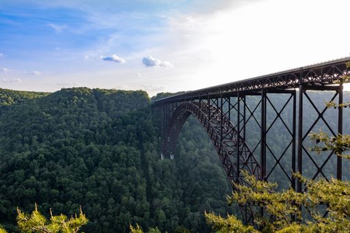 An angle shot of New River Gorge Bridge under the beautiful sky with green forest in the background