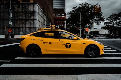 The view of  yellow Tesla Taxi driving by with the New York urban background