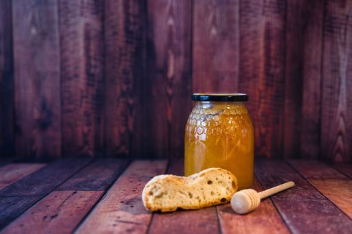 A closeup of a honey jar and bread in a wooden box