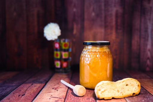 A closeup of a honey jar and bread in a wooden box