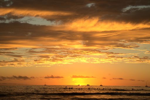 A mesmerizing sunset over the Waikiki Beach with silhouettes of surfers in Honolulu, Hawaii