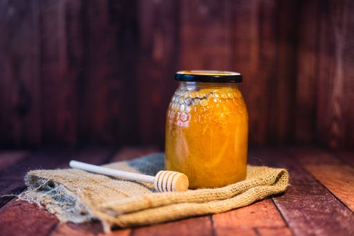 A closeup of a honey jar on a wooden surface