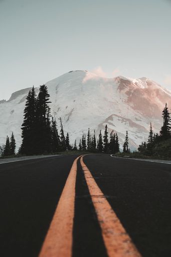 The close-up of asphalt yellow line road with snowy mountain background at Sunrise Park at Mt. Rainier in Washington