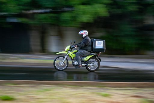A panning shot of a delivery guy riding a motorcycle on the road in Belo Horizonte, Brazil