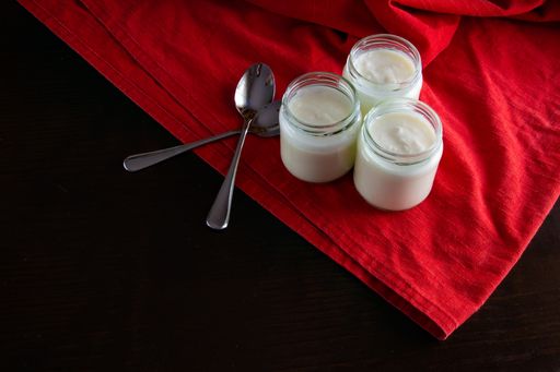 Three yogurts in glass jars on a red textile