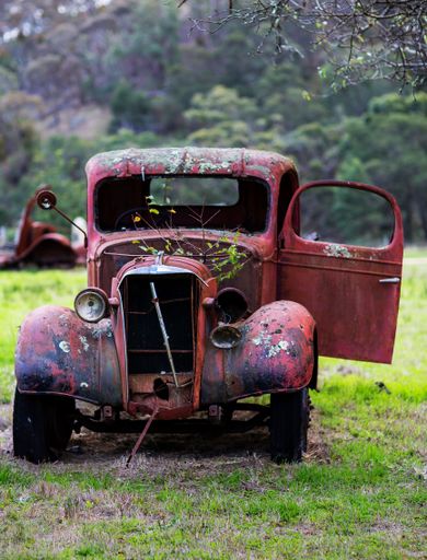 A vertical shot of an old wreck rusted car in a field