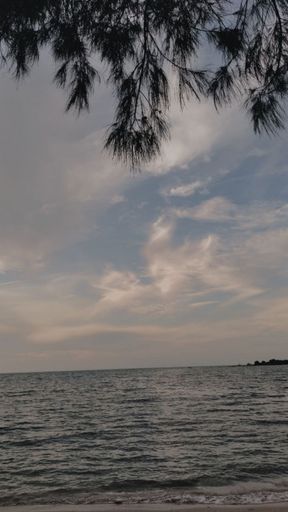 A Vertical shot of wavy sea water under a cloudy gray sky