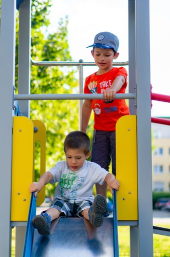 Two Polish Caucasian boys standing on a slide equipment in a playground