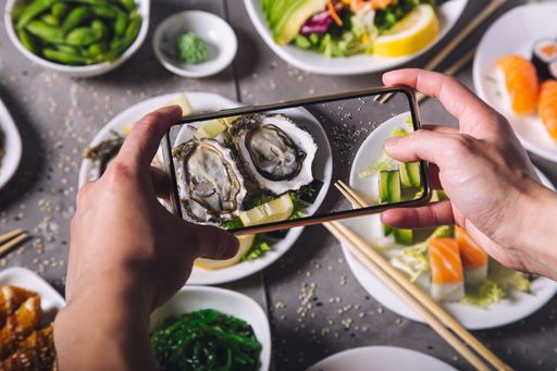 The hands take a photo of freshly served oysters. Japanese cuisine.