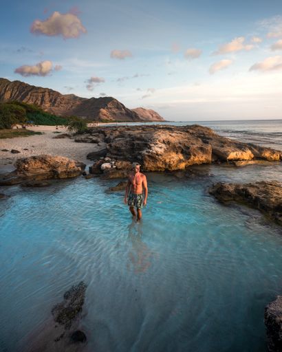 A male model standing in the water on background of rocks and boundless sea