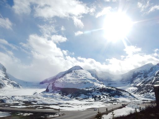 A mesmerizing view of the bright sun shining over the snowy hills