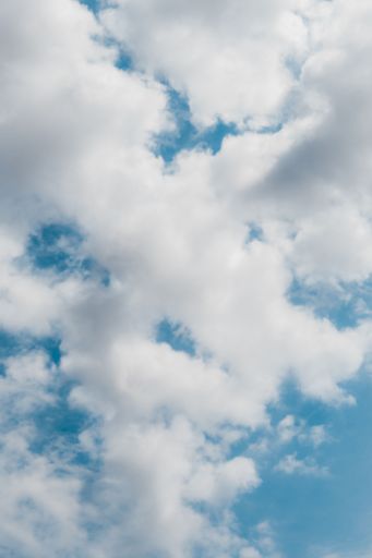 A vertical shot of a blue sky full of clouds, perfect for wallpaper