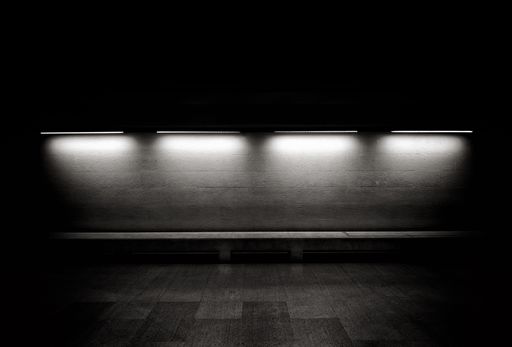 A greyscale shot of a bench with dark background