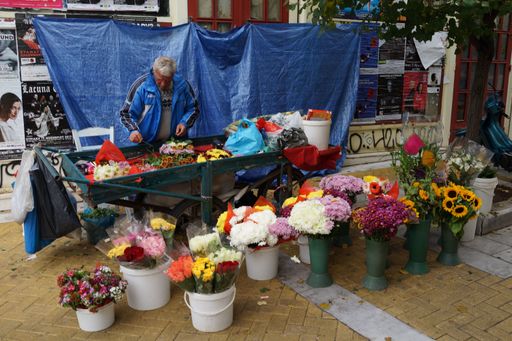 An old vendor selling flowers in a street flower market