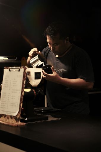The local barista making cappuccino by pouring milk in the coffee cup in Kepanjen, Indonesia