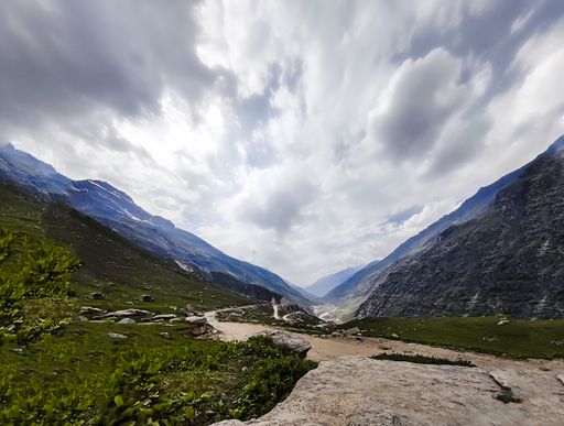 A narrow road in lush green valley between rocky mountains