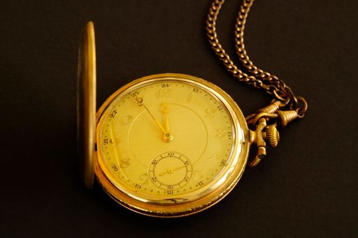A top view of an old gold-plated pocket watch against a black background