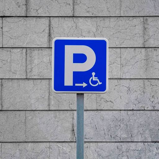 A wheelchair parking sign in blue with a big P on the background of a panel wall