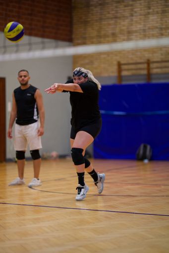 A vertical shot of a young female playing volleyball during a game in an indoor court