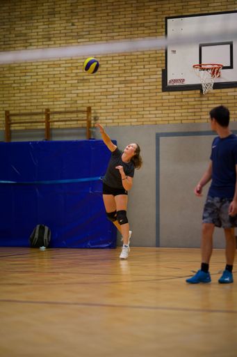 A vertical shot of a young female playing volleyball during a game in an indoor court