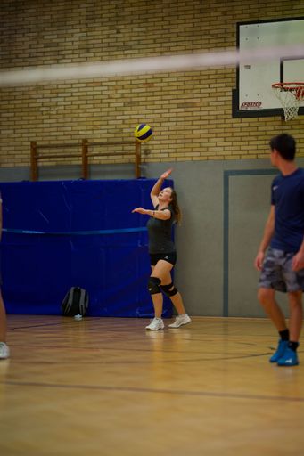 A vertical shot of a young female playing volleyball during a game in an indoor court