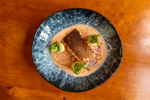 A top view of a pan fried salmon with cucumber rolls on a plate