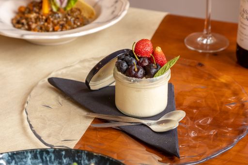 a closeup of a cheesecake in a cup with strawberries, cherries and blueberries