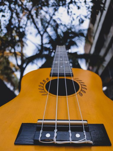 A low angle vertical shot of a classic yellow guitar with blurry background