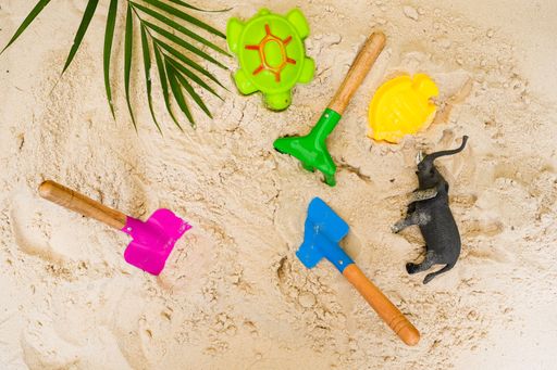 The top view of colorful toys on the sand including digging objects, turtle, and an elephant