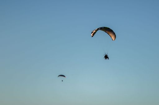 A closeup of two paragliders paragliding in the sky