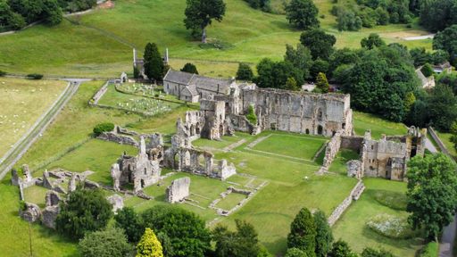 An aerial view of old ruins in a rural area surrounded by green nature