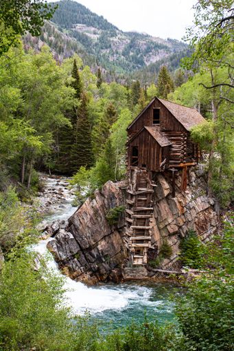 A vertical view of a green landscape with a small cottage house by the river