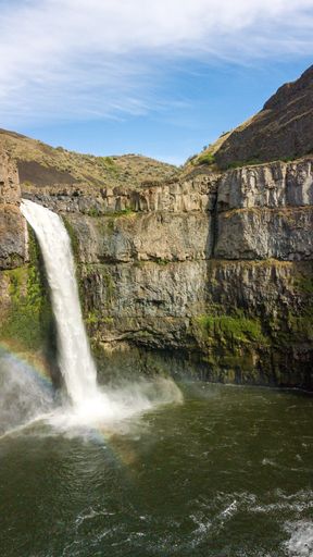 A vertical shot of the Palouse Falls with the rainbow over it in the United States