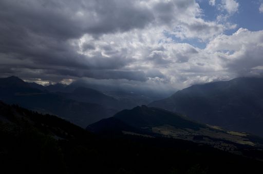The beautiful view of the sunlight penetrating through the clouds above the dark mountains.