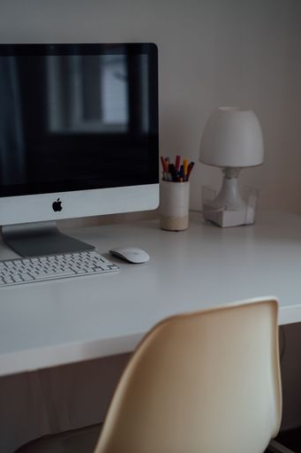 A vertical shot of the computer on the white working desk in a modern home office