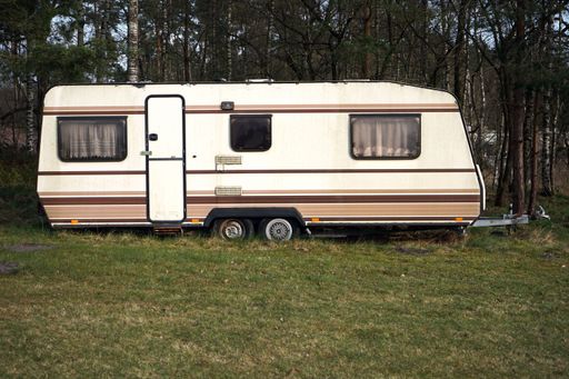 A closeup of a trailer home parked in a forest on front of the trees