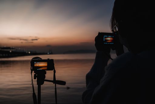 A closeup shot of a silhouette of a girl taking picture of the beautiful sunset in the evening