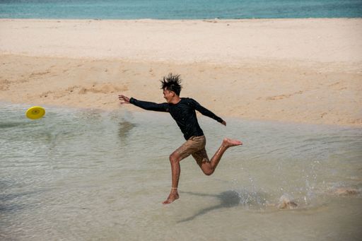 A boy happily playing with friends and trying to catch the frisbee