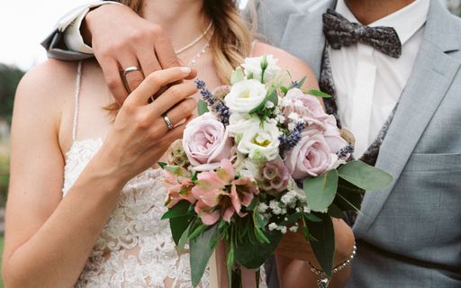 A closeup shot of a groom hugging the bride and holding her hand on the wedding day