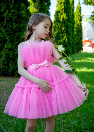 A vertical shot of a beautiful Caucasian little blonde girl wearing a pink dress