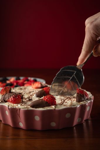 A vertical shot of a tasty cheesecake with different kinds of berries placed on a wooden surface