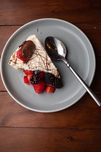 A top view of a tasty cheesecake with different kinds of berries placed on a grey plate